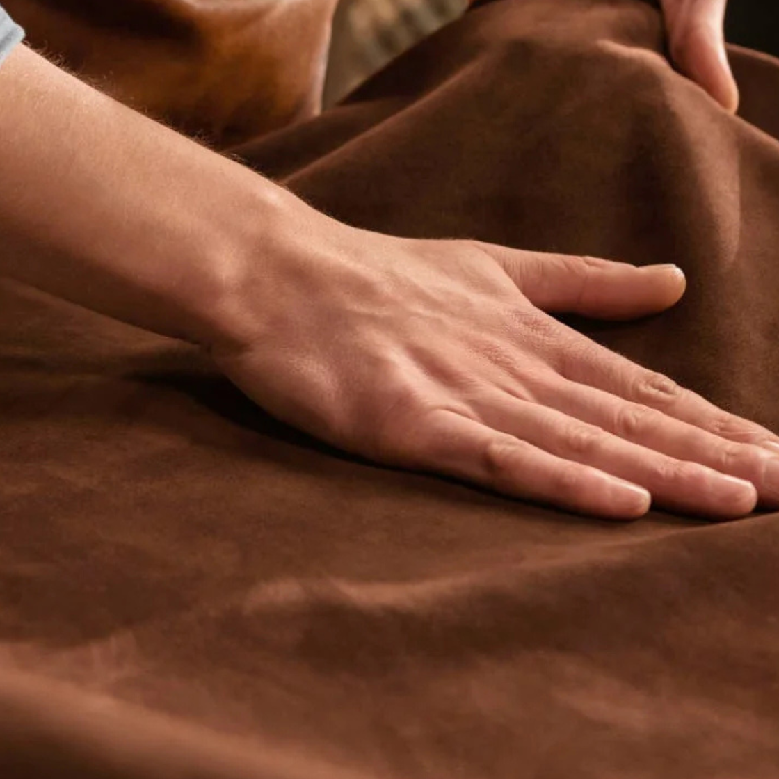 Person touching brown fabric with a blurred background